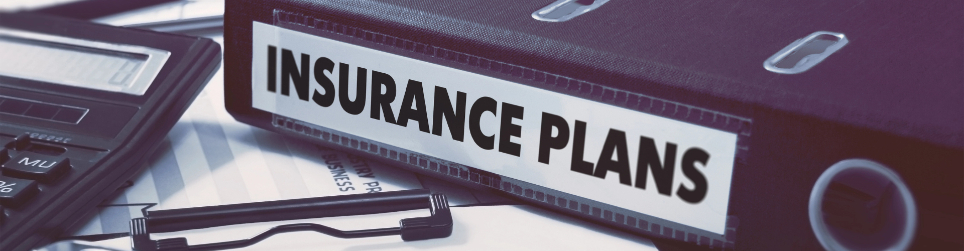 Desk with a book of insurance plans and a calculator